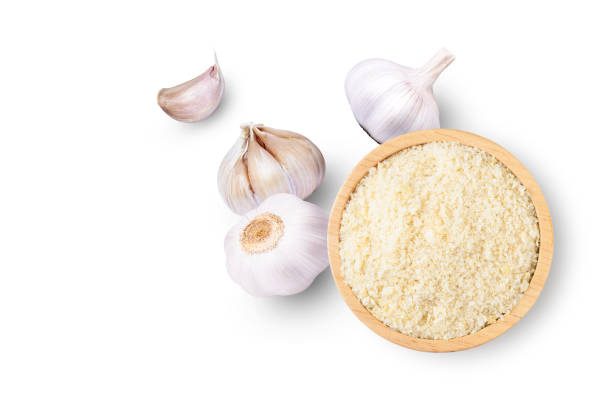 Garlic powder in wooden bowl with garlic bulb and clove isolated on white background. Top view. Flat lay. Copy space.